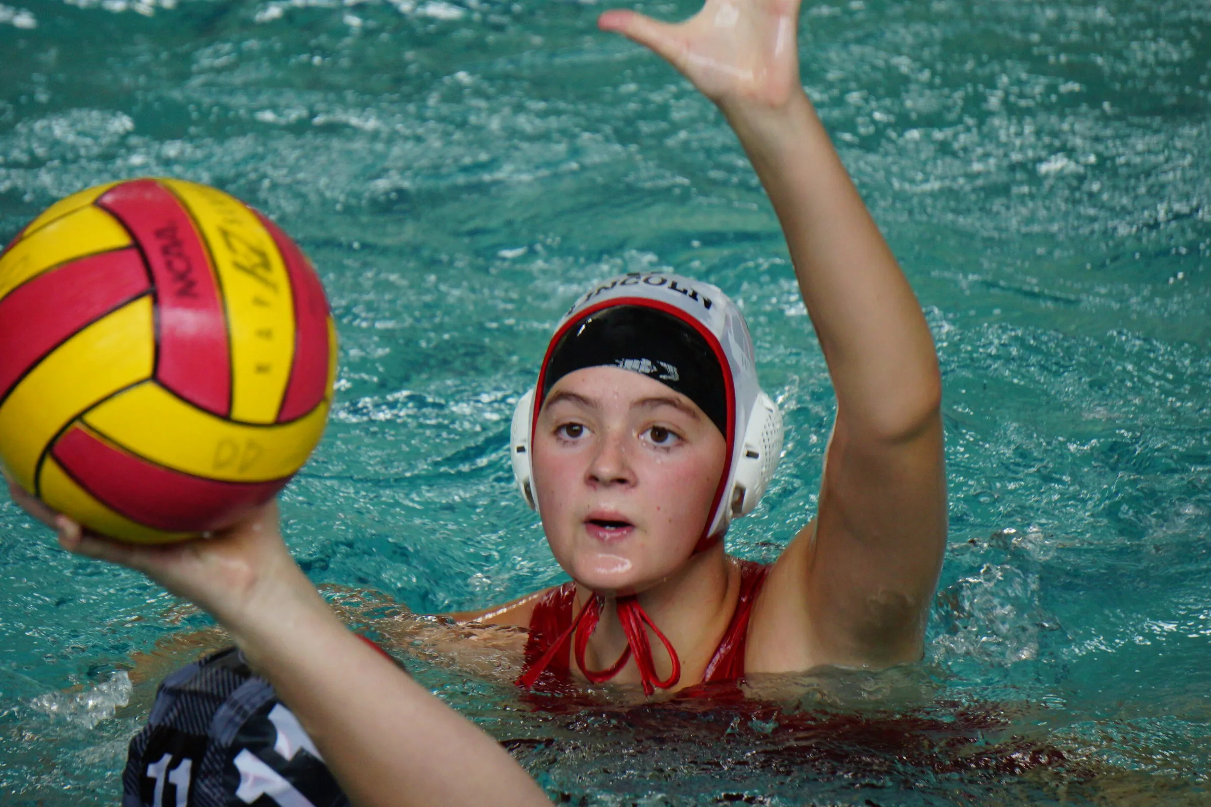 A Lincoln player holds the ball high, looking to pass