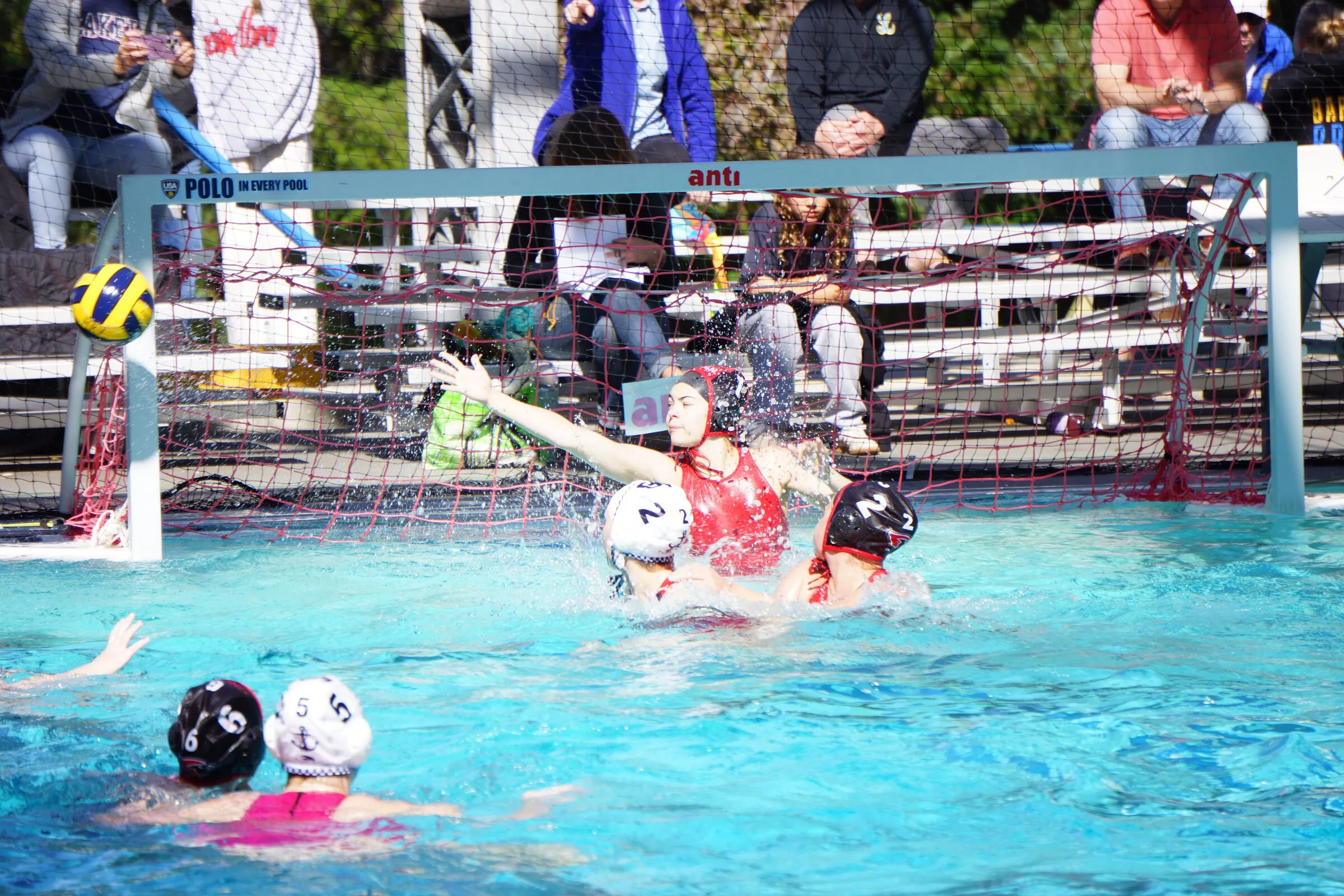 The goalie leaps to block a shot as the crowd watches