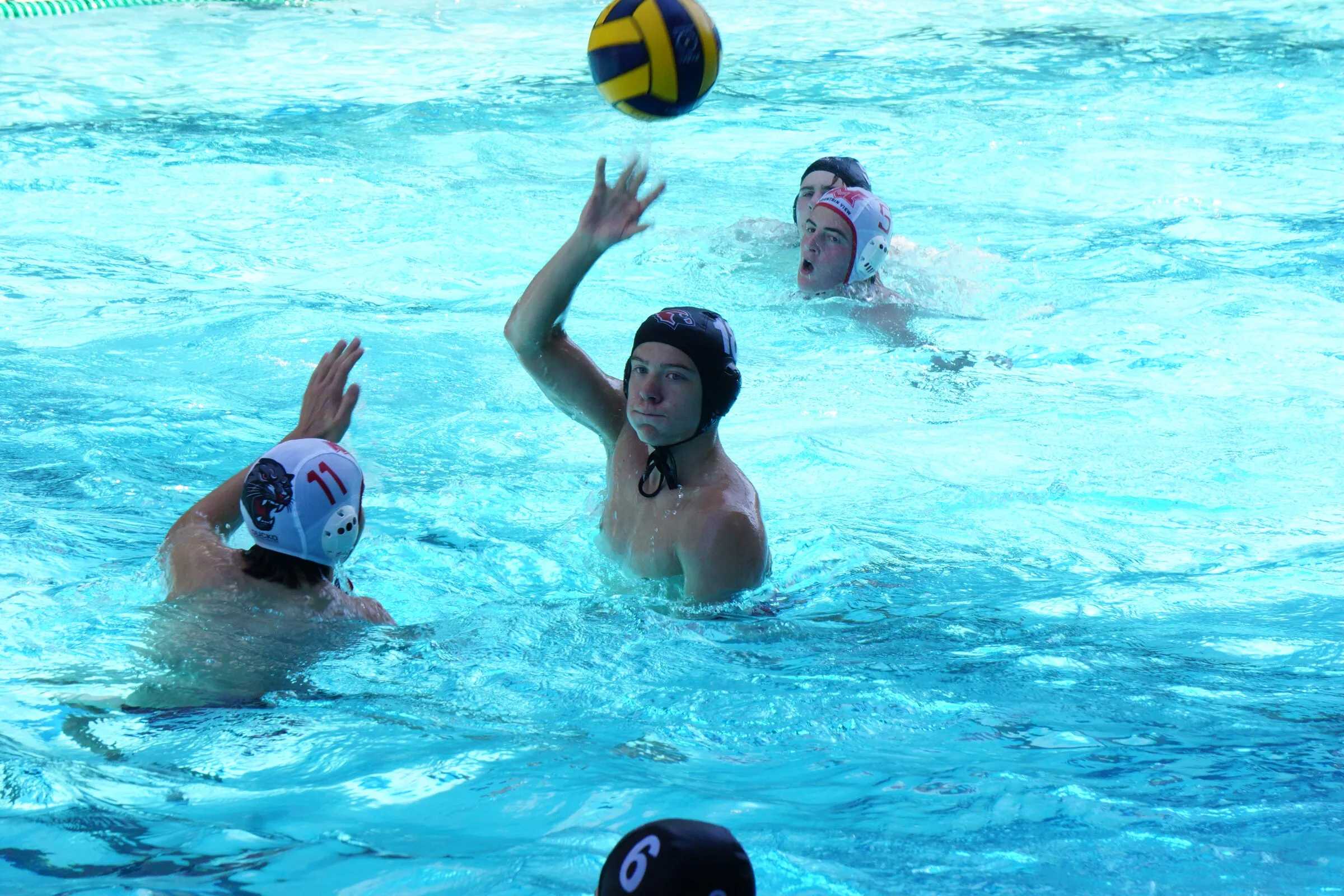 A player rises with the ball as teammates swim in