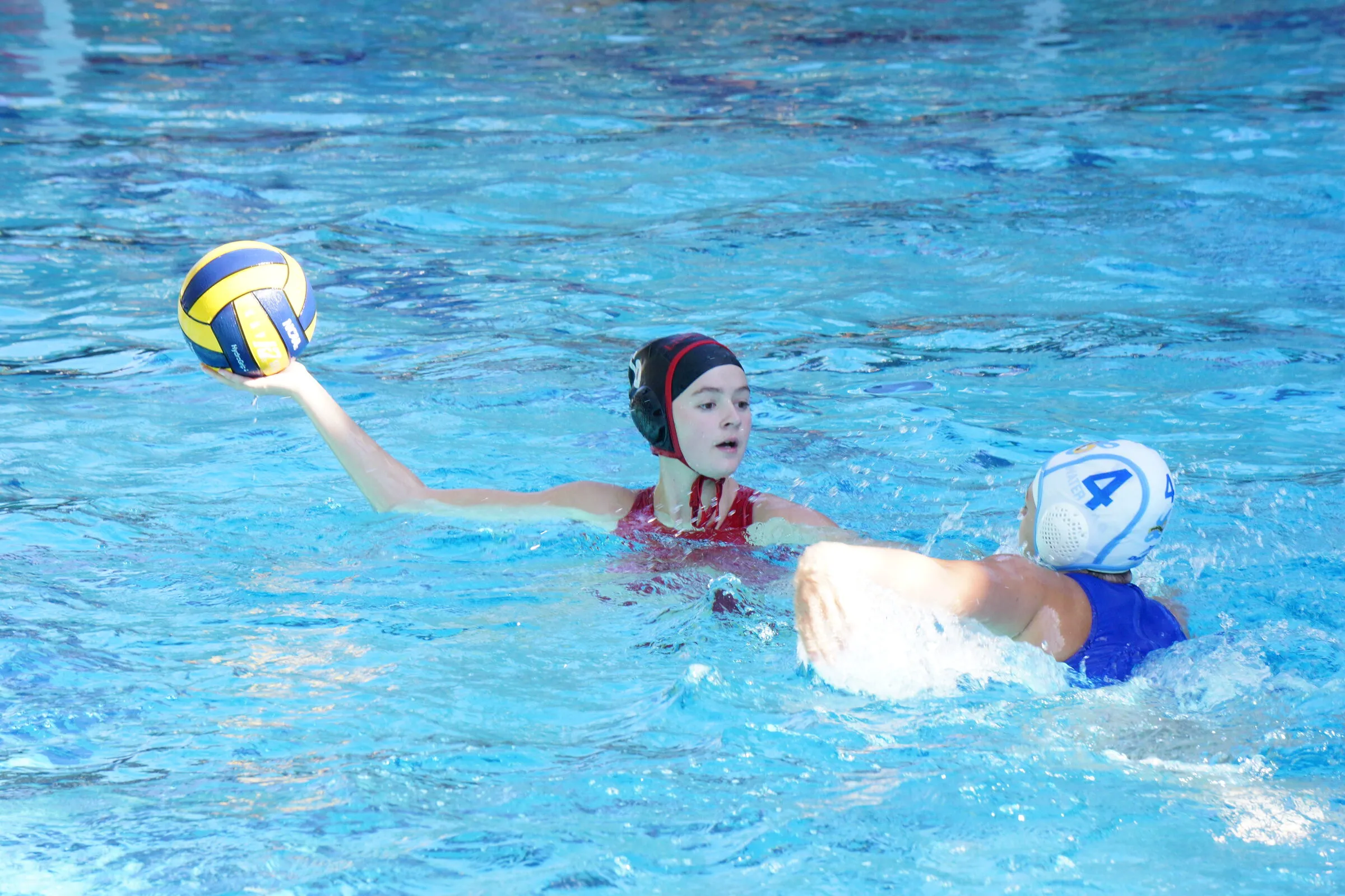 A player stretches for the ball ahead of a defender